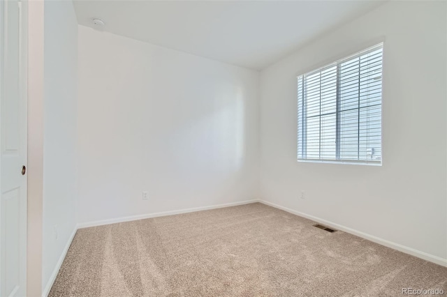 carpeted spare room with visible vents and baseboards