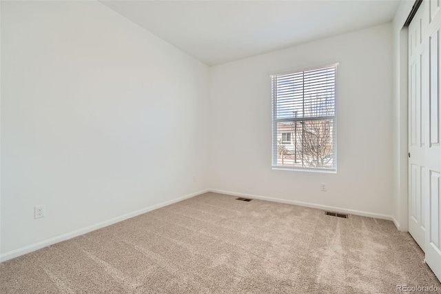 carpeted empty room featuring visible vents and baseboards