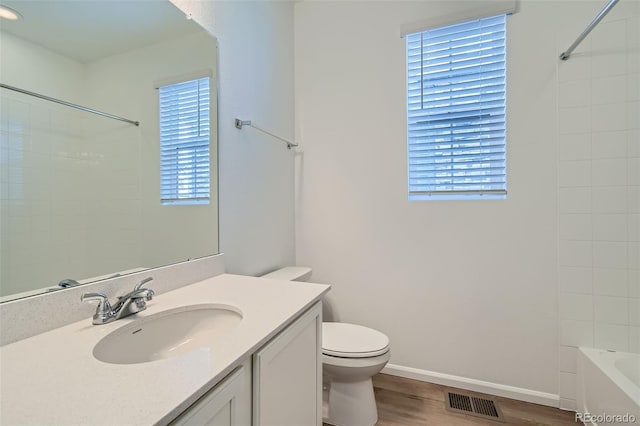 bathroom with a wealth of natural light, visible vents, toilet, and wood finished floors