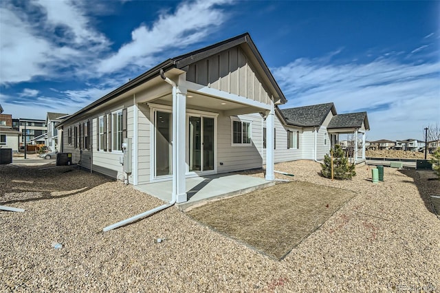 back of property featuring a patio area, a residential view, board and batten siding, and central AC