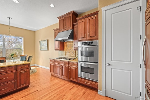 7003 S Irvington Ct, Aurora, CO 80016 - kitchen featuring stainless steel appliances, range hood, decorative backsplash, light wood-style floors, and a chandelier