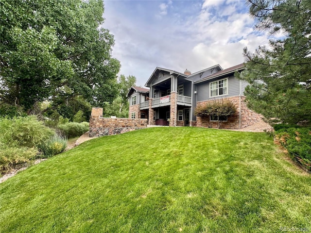 7003 S Irvington Ct, Aurora, CO 80016 - back of house featuring a yard, a balcony, stone siding, and a chimney