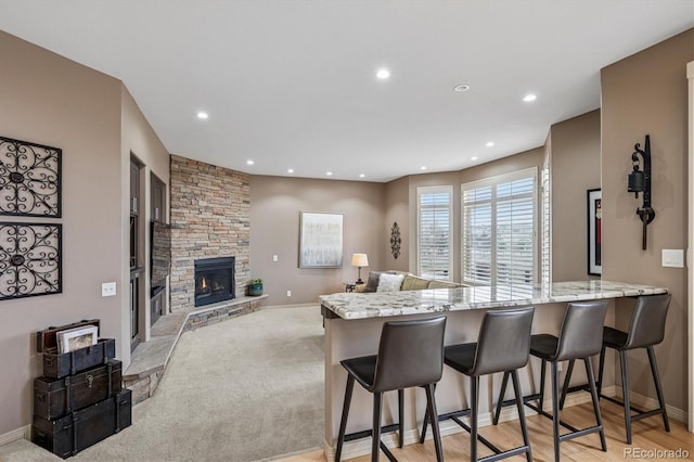6971 S Netherland Way, Aurora, CO 80016 - kitchen featuring recessed lighting, a kitchen breakfast bar, light stone counters, baseboards, and a peninsula