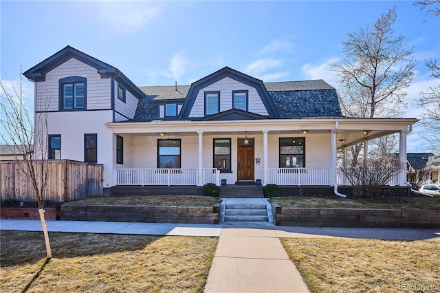 view of front facade featuring brick siding, a gambrel roof, a porch, and a shingled roof