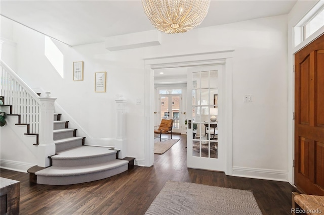 entryway with stairs, a notable chandelier, baseboards, and dark wood-style flooring