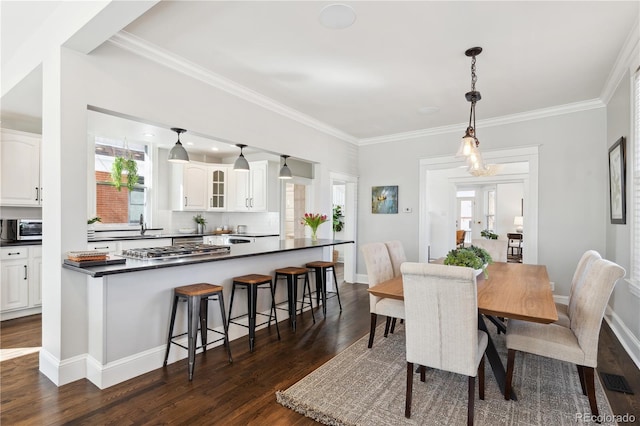 dining room with baseboards, crown molding, dark wood-style flooring, and a toaster