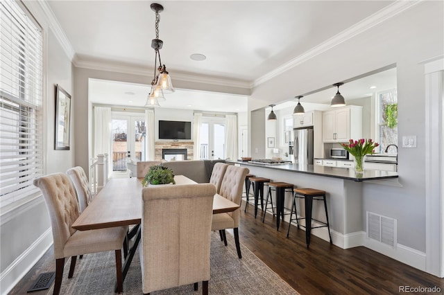 dining space featuring dark wood finished floors, visible vents, french doors, and crown molding