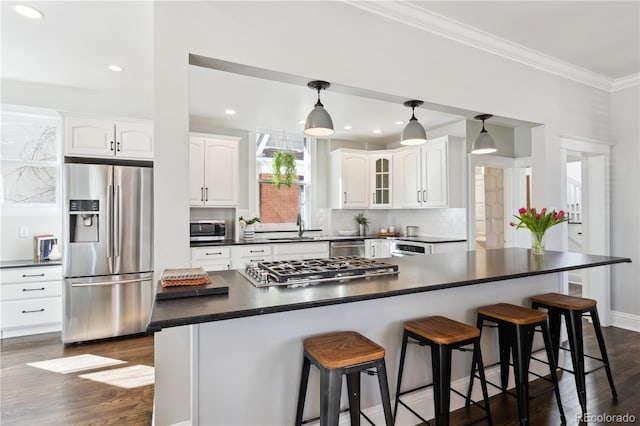 kitchen with a sink, dark countertops, white cabinetry, stainless steel appliances, and crown molding