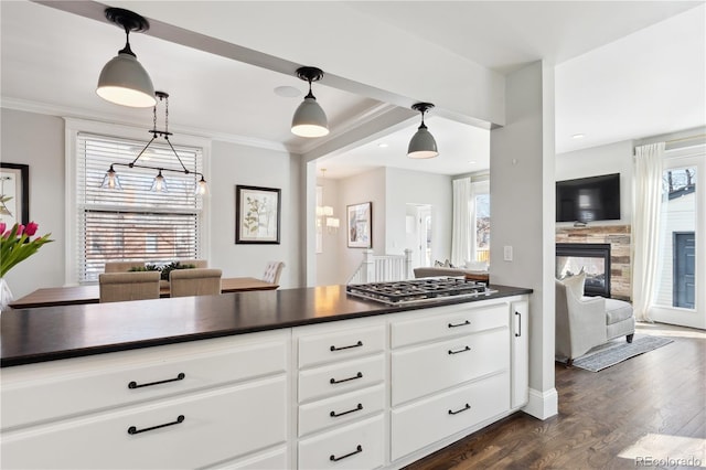 kitchen with ornamental molding, dark countertops, open floor plan, dark wood finished floors, and stainless steel gas stovetop