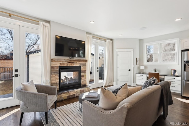 living area with recessed lighting, french doors, a stone fireplace, and dark wood-style flooring