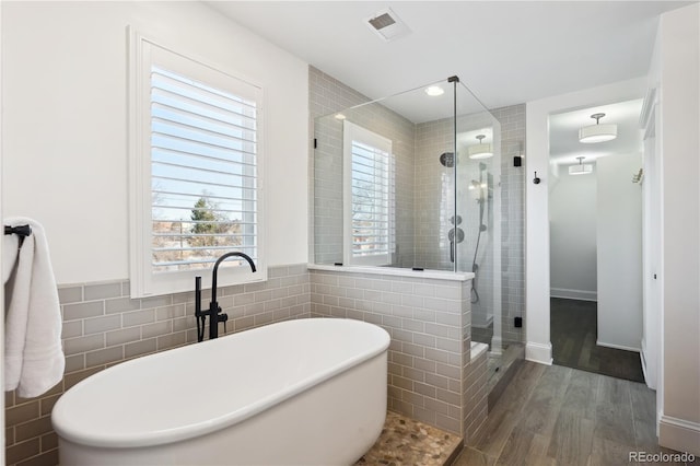 full bathroom with a freestanding tub, visible vents, a stall shower, wood finished floors, and tile walls