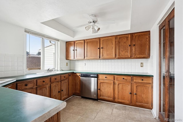 kitchen featuring a raised ceiling, sink, stainless steel dishwasher, and decorative backsplash