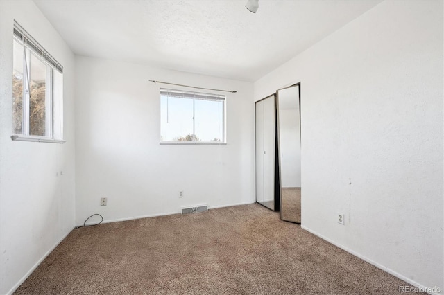 unfurnished bedroom featuring a closet, a textured ceiling, and carpet flooring