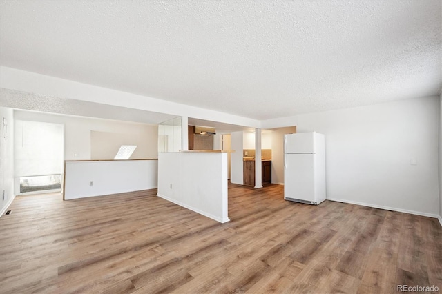 unfurnished living room featuring light hardwood / wood-style flooring and a textured ceiling