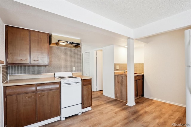 kitchen featuring extractor fan, tasteful backsplash, white appliances, a textured ceiling, and light hardwood / wood-style flooring