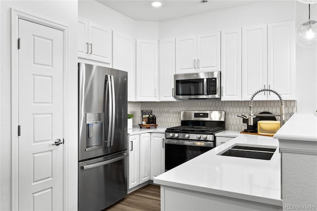kitchen with light countertops, decorative backsplash, white cabinets, and stainless steel appliances