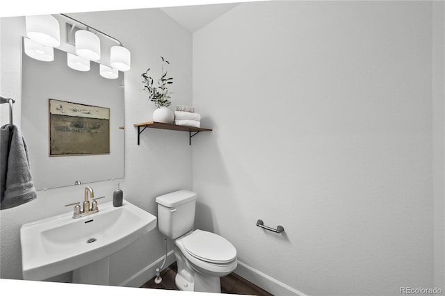 bathroom with baseboards, a sink, wood finished floors, and toilet