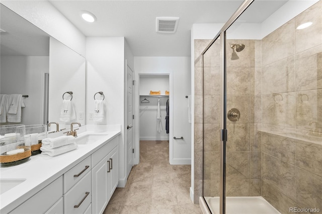 full bath with a sink, a shower stall, double vanity, and visible vents