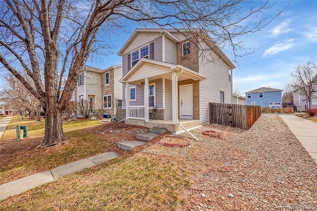 traditional-style house featuring covered porch and fence