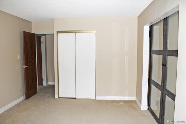 unfurnished bedroom featuring light carpet, a textured ceiling, and baseboards