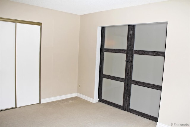 unfurnished bedroom with a closet, light carpet, and baseboards