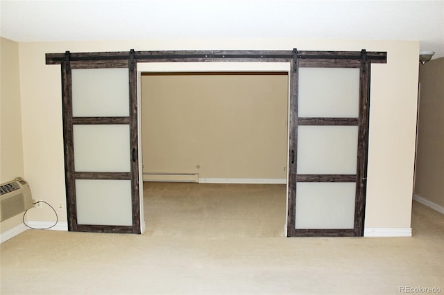 empty room featuring a barn door, a baseboard radiator, carpet flooring, and baseboards