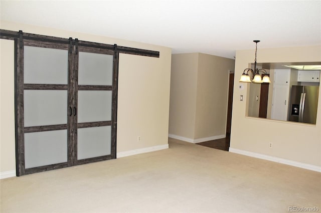 carpeted spare room with a barn door, baseboards, and a notable chandelier