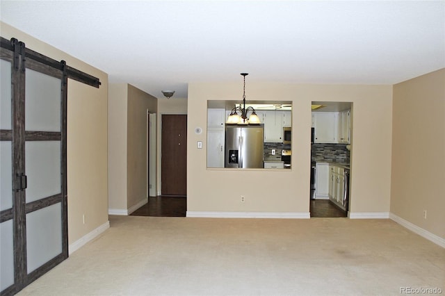 spare room with baseboards, dark colored carpet, and an inviting chandelier