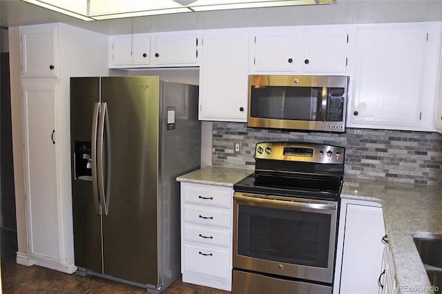 kitchen featuring stainless steel appliances, light stone countertops, white cabinets, and tasteful backsplash