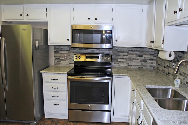 kitchen with decorative backsplash, appliances with stainless steel finishes, light stone countertops, white cabinetry, and a sink