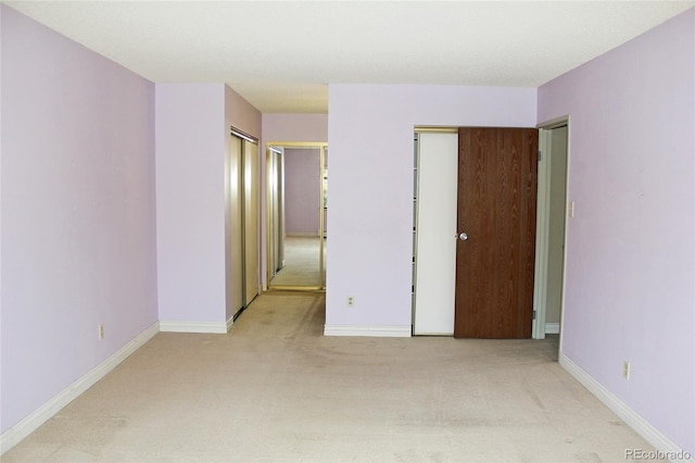 unfurnished bedroom with baseboards, two closets, and light colored carpet