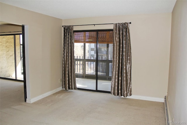 unfurnished room with a baseboard heating unit, carpet flooring, and baseboards