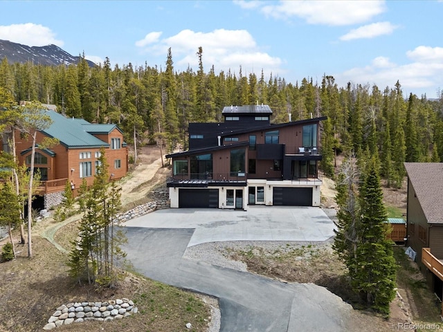 436 N Fuller Placer Rd, Breckenridge, CO 80424 - rear view of house with driveway, a balcony, an attached garage, a wooded view, and a mountain view