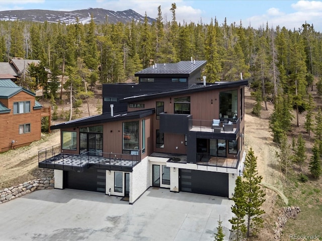 436 N Fuller Placer Rd, Breckenridge, CO 80424 - back of house with an attached garage, a balcony, a view of trees, and driveway