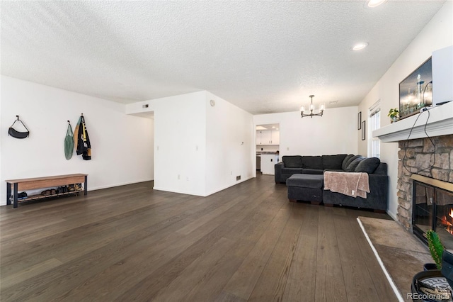 living area with a chandelier, dark wood-type flooring, a fireplace, a textured ceiling, and recessed lighting