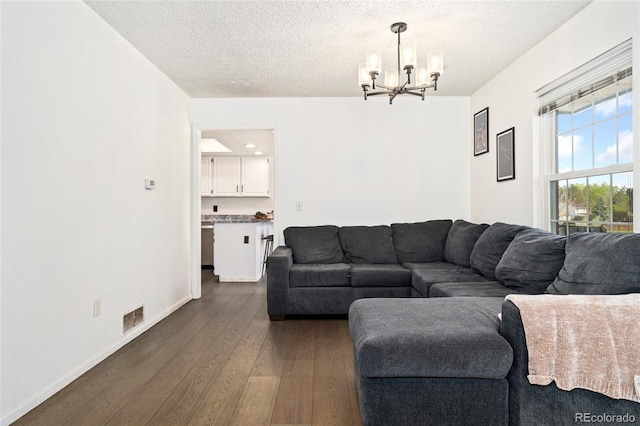 living room featuring a chandelier, a textured ceiling, dark wood-style flooring, and baseboards
