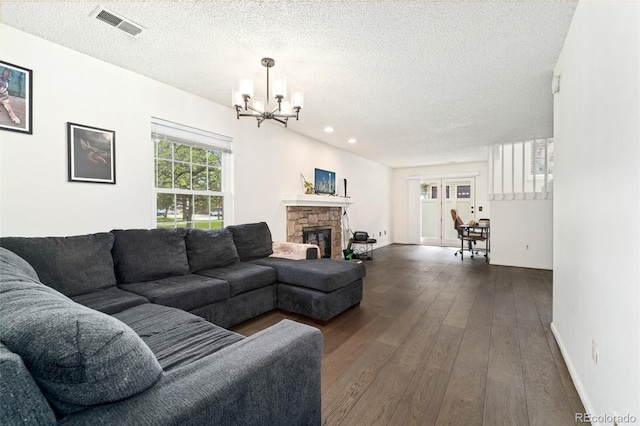 living area with a chandelier, a textured ceiling, dark wood-style floors, a fireplace, and baseboards