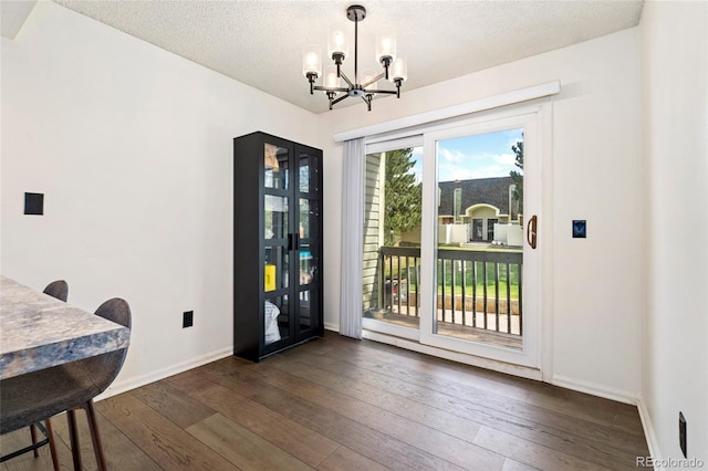 dining area with a chandelier, dark wood-type flooring, baseboards, and a textured ceiling