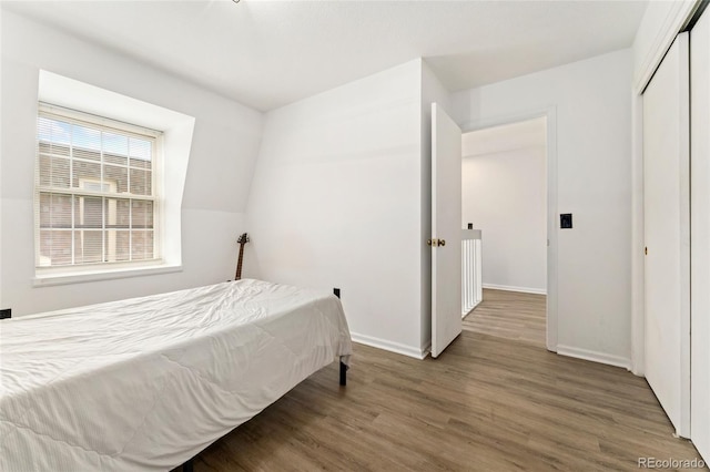 bedroom with wood finished floors, baseboards, and a closet