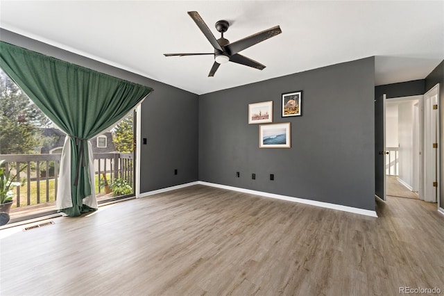 spare room with wood finished floors, a ceiling fan, healthy amount of natural light, and baseboards