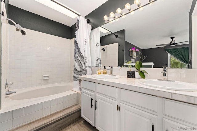 full bath with tiled shower / bath, double vanity, a ceiling fan, and wood finished floors