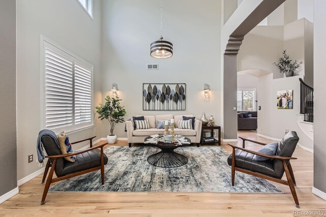 989 Graland Pl, Highlands Ranch, CO 80126 - living room featuring a towering ceiling, arched walkways, wood finished floors, baseboards, and stairway