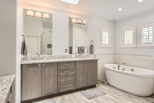 989 Graland Pl, Highlands Ranch, CO 80126 - full bath featuring double vanity, a freestanding tub, a shower stall, wood finished floors, and recessed lighting