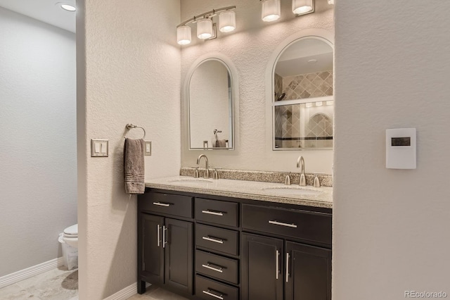 989 Graland Pl, Highlands Ranch, CO 80126 - full bathroom featuring toilet, double vanity, a tile shower, and baseboards