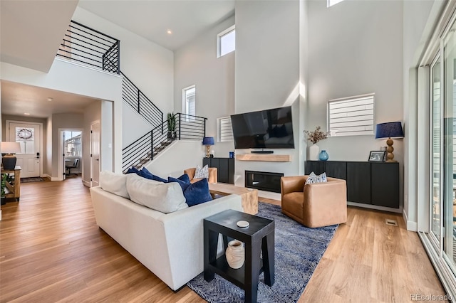 2840 E 102nd Pl, Thornton, CO 80229 - living area featuring a high ceiling, light wood-type flooring, a glass covered fireplace, stairway, and recessed lighting