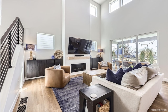 2840 E 102nd Pl, Thornton, CO 80229 - living area featuring a high ceiling, wood finished floors, a glass covered fireplace, and baseboards