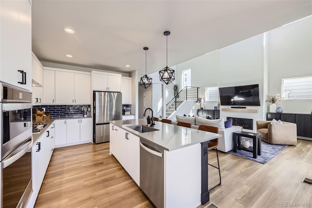 2840 E 102nd Pl, Thornton, CO 80229 - kitchen with stainless steel appliances, a sink, light wood-style floors, a kitchen breakfast bar, and hanging light fixtures