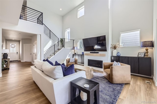 2840 E 102nd Pl, Thornton, CO 80229 - living area featuring a towering ceiling, light wood-style flooring, stairs, and a glass covered fireplace