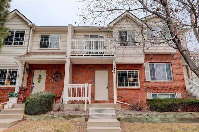 multi unit property with a balcony and brick siding