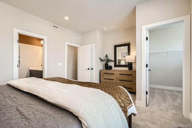 carpeted bedroom with ensuite bath, a closet, and a walk in closet